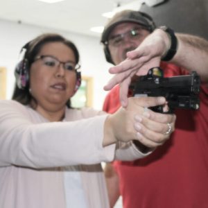 A woman aiming handgun with shooting class instructor in Oklahoma City, OK